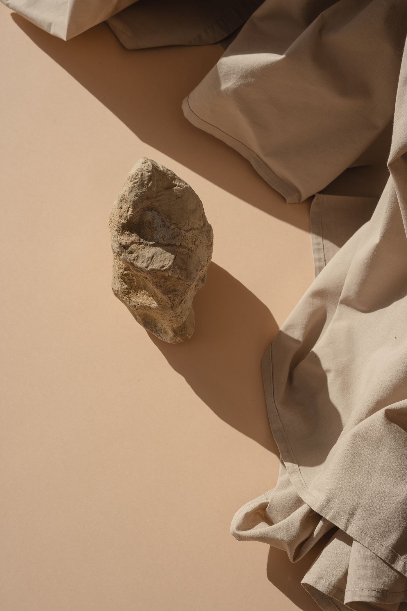 A weathered stone and soft beige linen in warm sunlight